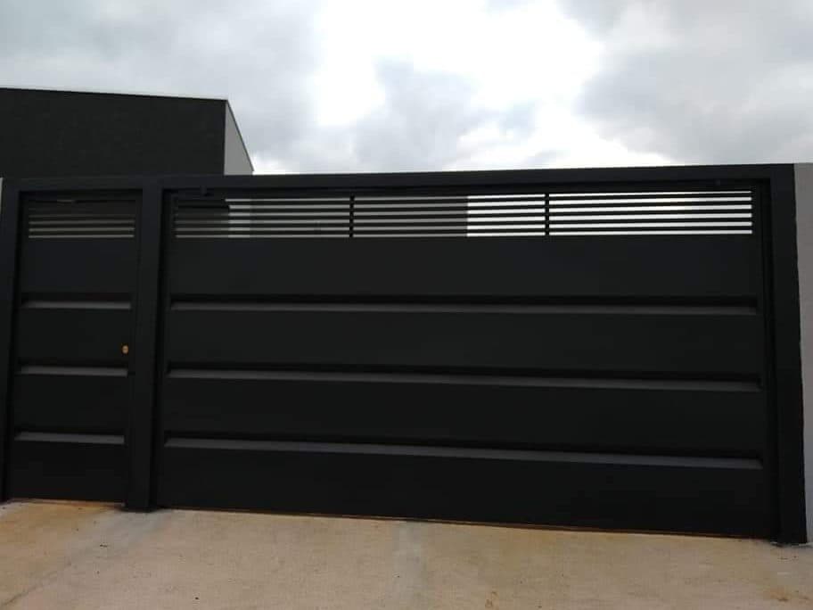 Portão de aço preto com portão social, instalado na garagem de uma casa